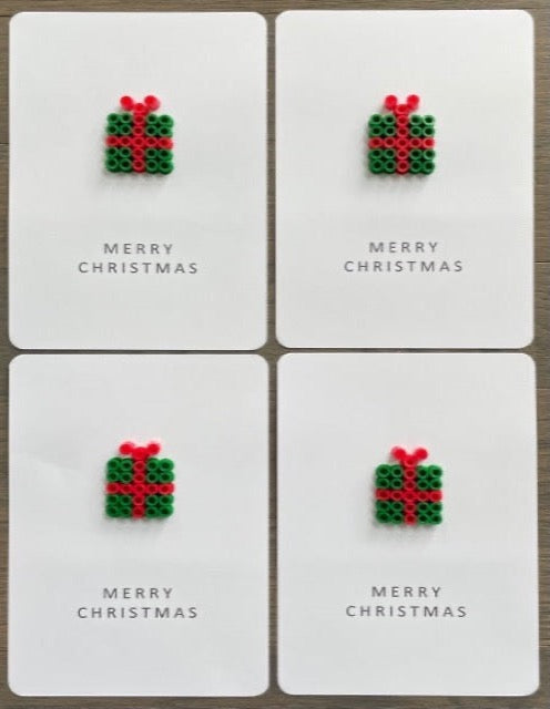Picture of a set of 4 Merry Christmas cards that have a dark green gift with red ribbon on each one