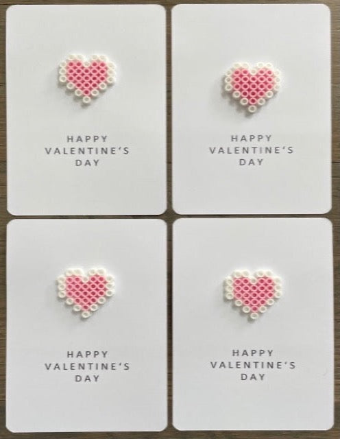 Picture of a set of 4 Happy Valentine's Day cards that each have a pink and white heart on it.