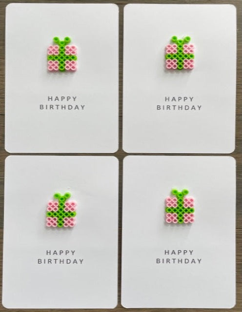 Picture of a set of 4 Happy Birthday cards that have a pink gift with lime green ribbon on each card
