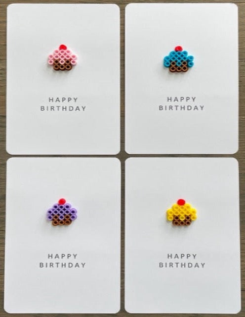 Picture of a set of 4 cupcake happy birthday cards. One is a pink cupcake, one is a blue cupcake, one is a purple cupcake, and one is a yellow cupcake.