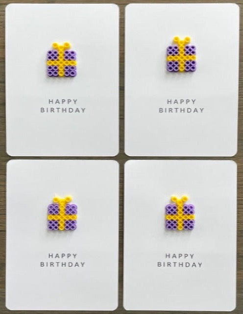 Picture of a set of 4 Happy Birthday cards that each have a purple with yellow ribbon gift box on them 
