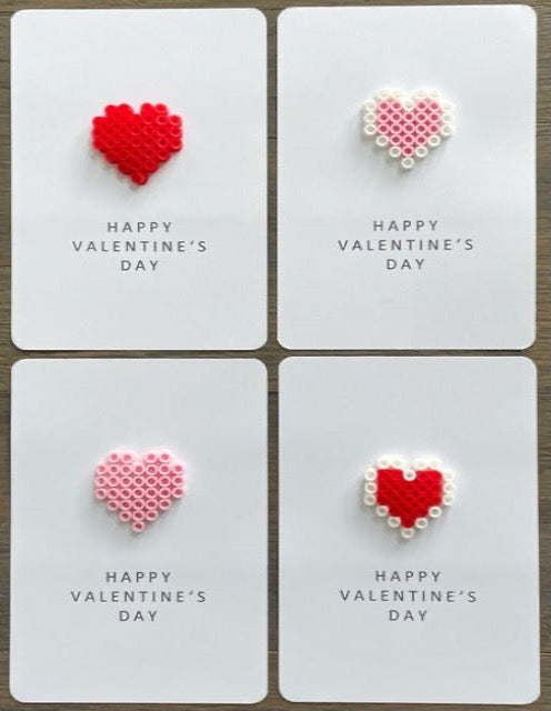 Picture of a set of 4 Happy Valentine's cards. One card  has a red heart, one card has a red and white heart, one card has a pink heart, and one card has a pink and white heart.