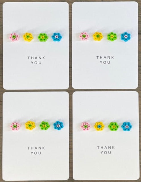 Picture of a set of 4 Thank You cards that have 4 flowers across each card.  The flowers are pink, yellow, lime green, and blue