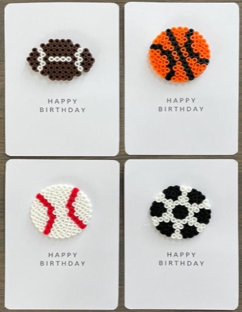 Picture of a set of 4 sports ball Happy Birthday cards.  One card has a football on it, one has a basketball on it, one has a baseball on it, and one has a soccer ball on it