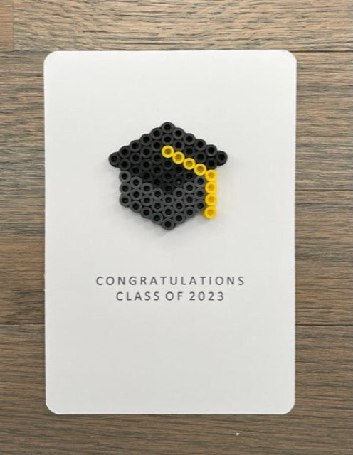 Picture of a congratulations class of 2023 card with a dark gray and black graduation cap with a yellow tassel