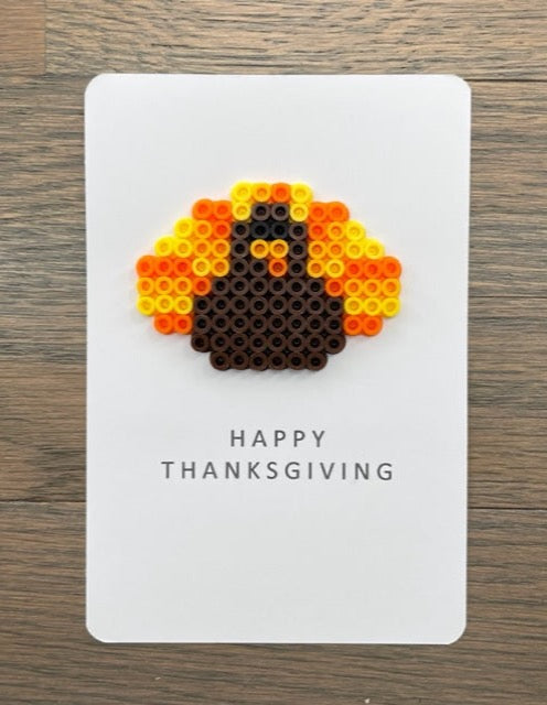 Picture of a Happy Thanksgiving card with a dark brown, orange, yellow  turkey on it.