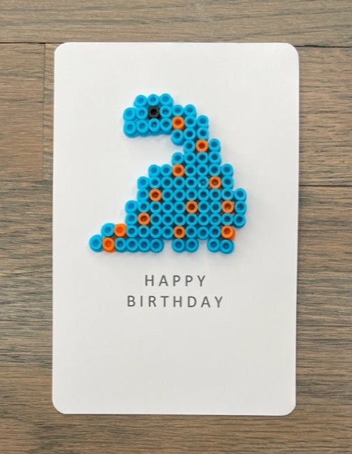 Picture of a Happy Birthday card with a blue with orange spots dinosaur on it