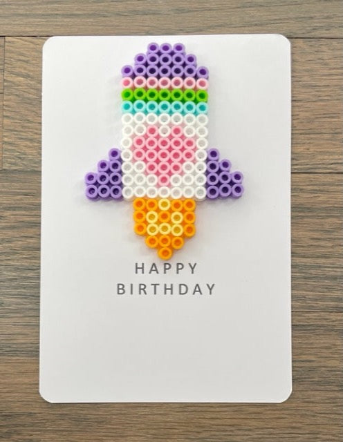 Picture of a Happy Birthday card with a white, purple, pink, lime green, light blue rocket on it