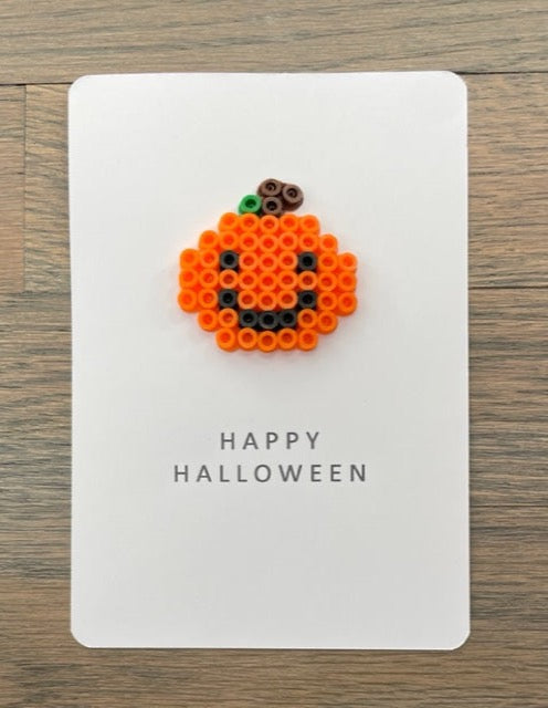 Picture of a Happy Halloween card with an orange pumpkin that has black eyes and a black smile