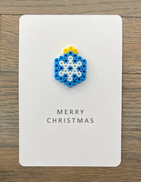 Picture of a Merry Christmas card with blue ornament that has white snowflake on it