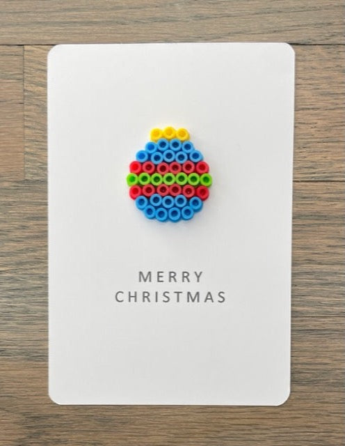 Picture of a Merry Christmas card with blue, red, lime green ornament on it