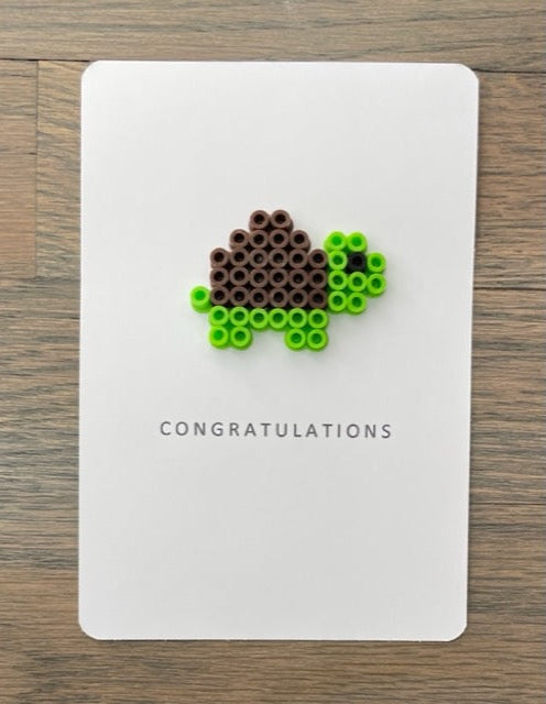 Picture of a congratulations card that has a lime green, dark brown turtle on it