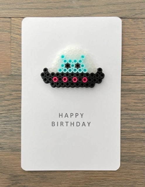 Picture of black and hot pink spacecraft with light blue alien Birthday card