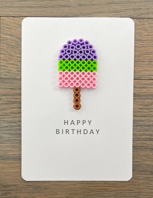 Picture of a Happy Birthday card with a purple, lime green, and pink popsicle on it
