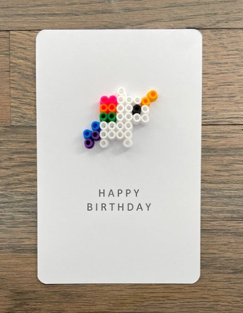 Picture of a Happy Birthday card that has a small white unicorn on it.