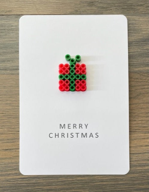 Picture of a Merry Christmas card that has a red with green ribbon gift box on it