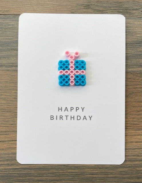 Picture of a Happy Birthday card that has a blue gift with pink ribbon on it