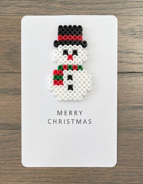 Picture of snowman wearing  a red and green scarf on a Merry Christmas card.