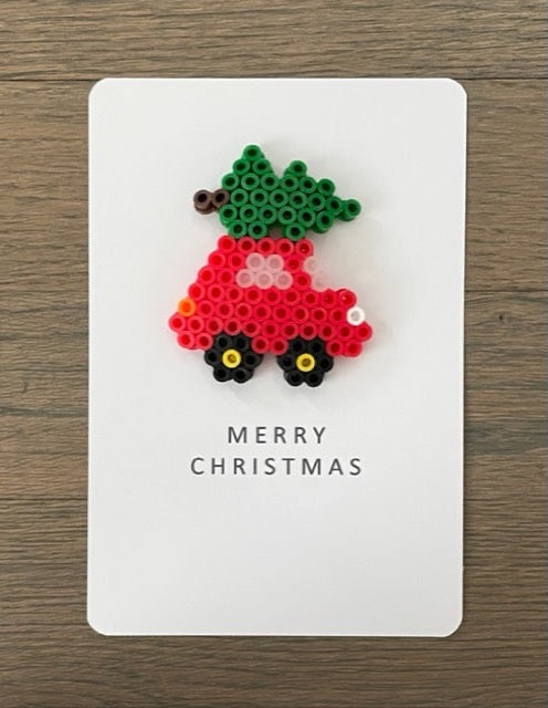 Picture of Merry Christmas card that has a red card with a Christmas tree on top of it.