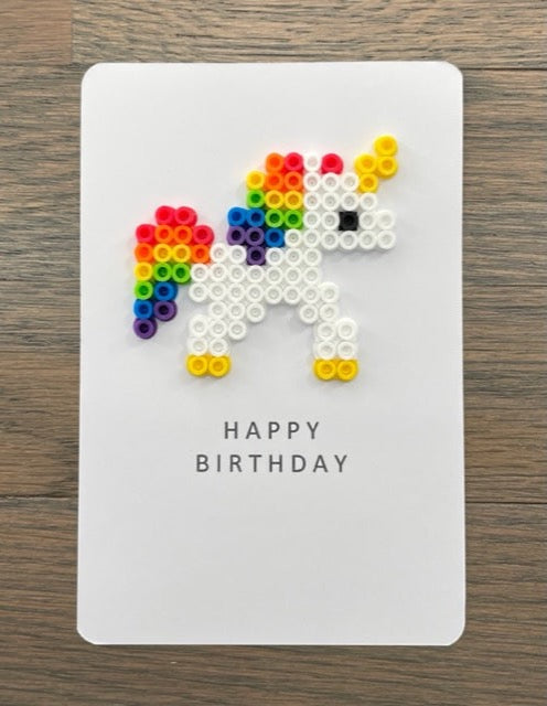 Picture of a Happy Birthday card that has a white unicorn with rainbow tail on it